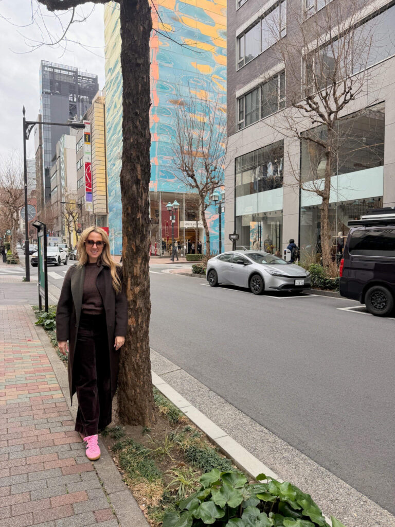 Woman standing beside a tree on a Ginza street with the colorful Louis Vuitton building behind her