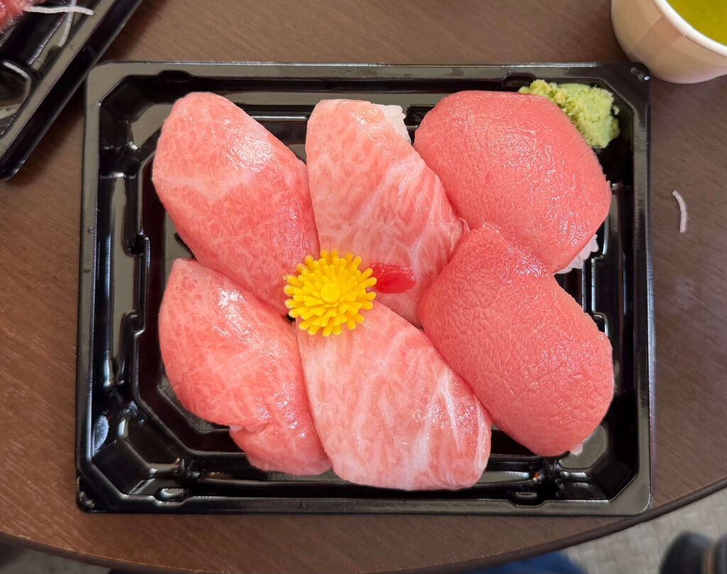 Tray of five tuna nigiri arranged in a flower shape with a yellow garnish in the center, from Maguroya Kurogin at the Tsukiji Outer Market