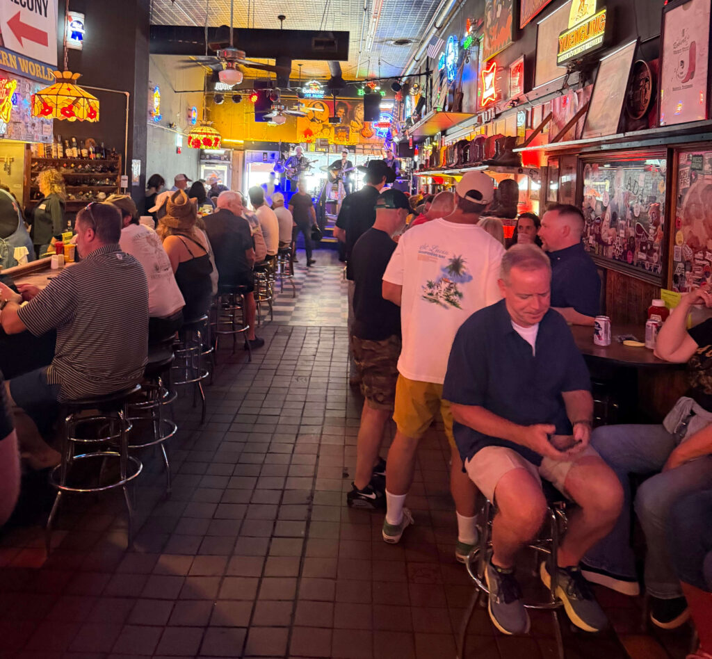 Crowded bar inside Robert's Western World with a live band and boots displayed on a shelf