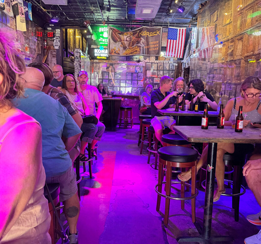Crowd seated on bar stools inside Tootsie's Orchid Lounge under purple lights